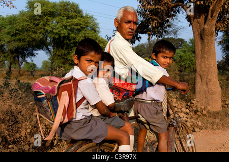 Il vecchio uomo con i bambini in bicicletta road Khajuraho-Varanasi, India Foto Stock