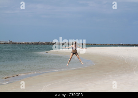 La donna caucasica facendo un salto a stella su una bellissima spiaggia Foto Stock