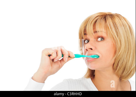 Dettaglio ritratto di una felice e si chiedeva come donna matura spazzolare i suoi denti isolati su sfondo bianco con copyspace Foto Stock