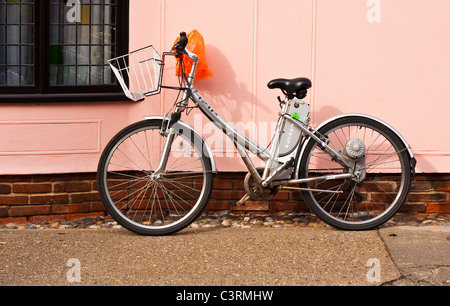 Ladies bike appoggiato contro una parete rosa Foto Stock