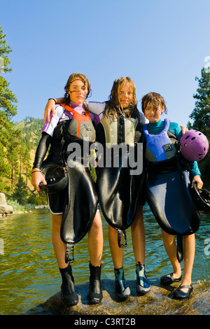 Wet ragazze caucasiche in piedi vicino al fiume in kayak gear Foto Stock