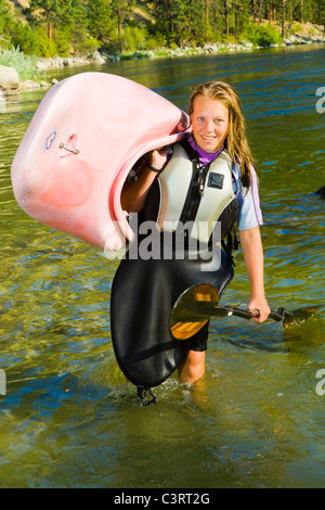 Adolescente caucasici che trasportano i kayak in fiume Foto Stock