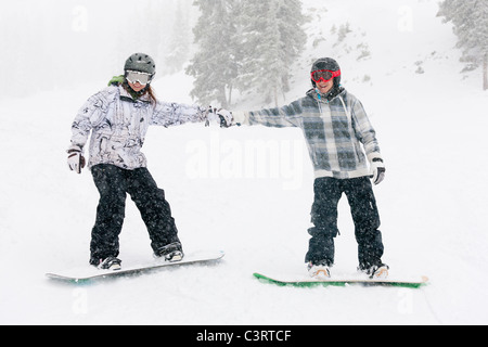 Gli appassionati di snowboard tenendo le mani sulla pista da sci Foto Stock