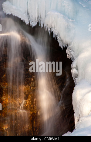 Acqua in movimento di Holland Lake Falls accanto a una formazione di ghiaccio nel Seeley Swan Valley del Montana Foto Stock