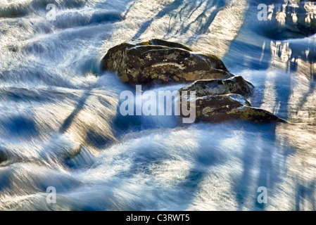 Il sole illumina le rocce in medio di raging allagata nel fiume Smoky Mountains Foto Stock