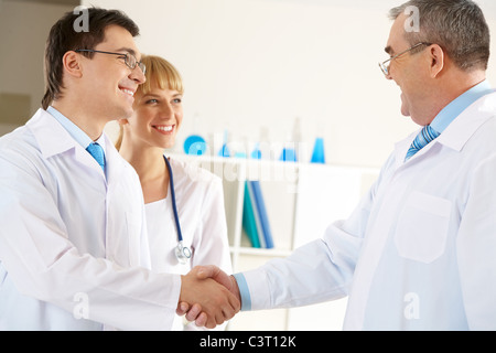 Foto di età compresa tra medico e il giovane medico con handshake friendly infermiera vicino Foto Stock