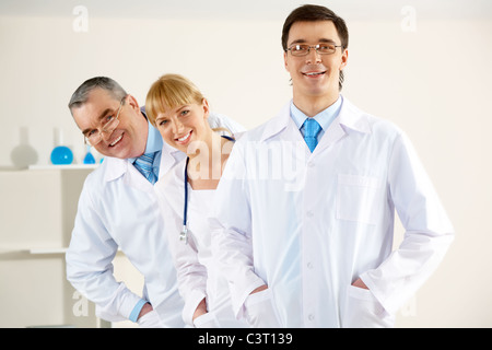 Ritratto di terapisti amichevole in piedi in linea e guardando la fotocamera con felice medico nella parte anteriore Foto Stock