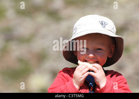 Un giovane ragazzo sat gustando un drink e un picnic al Kreuzboden nella valle di Saas, Svizzera. Foto Stock