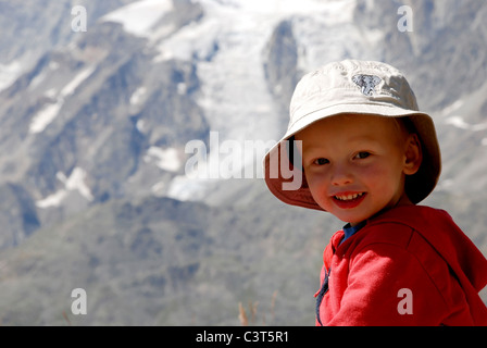 Un giovane ragazzo sat gustando un drink e un picnic al Kreuzboden nella valle di Saas, Svizzera. Foto Stock