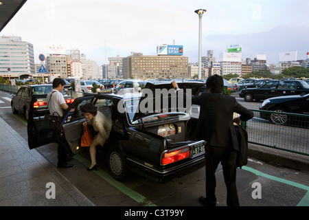 Donna arrivare al di fuori di un taxi a Shin-Osaka stazione ferroviaria, Giappone. Foto Stock