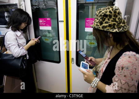 Due donne giapponesi utilizzando i telefoni cellulari, Tokyo, Giappone Foto Stock