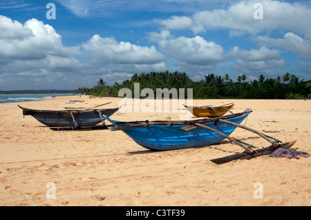 Spiaggiata canoe outrigger Marakolliya Tangalla spiaggia costa meridionale dello Sri Lanka Foto Stock