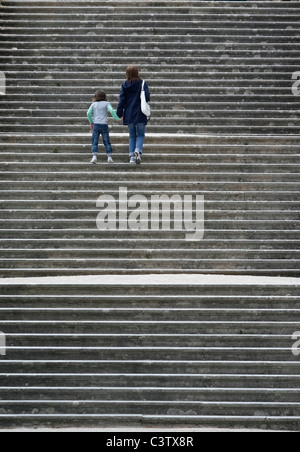 Donna e bambino a camminare su un set di scale Foto Stock