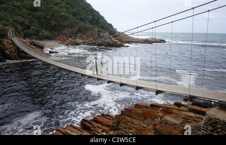 Madre e figlia camminare sopra il ponte di sospensione a Stormsriver bocca; Tsitsikamma - Provincia del Capo occidentale - Africa del Sud Foto Stock