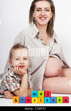 Donna incinta con suo figlio e coloratissimi blocchi in legno Foto Stock