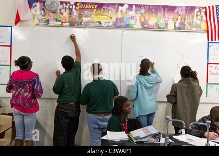 Gli studenti afroamericani scrivere equazioni chimiche a bordo in chimica classe a Rapoport Accademia pubblica scuola charter a Waco Foto Stock