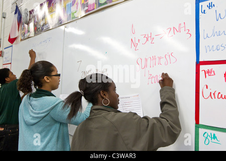 Gli studenti afroamericani scrivere equazioni chimiche a bordo in chimica classe a Rapoport Accademia pubblica scuola charter a Waco Foto Stock