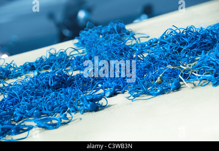 Cumulo di cuffie blu con cavi aggrovigliati in un pasticcio. DOF poco profondo, la messa a fuoco al centro. Foto Stock