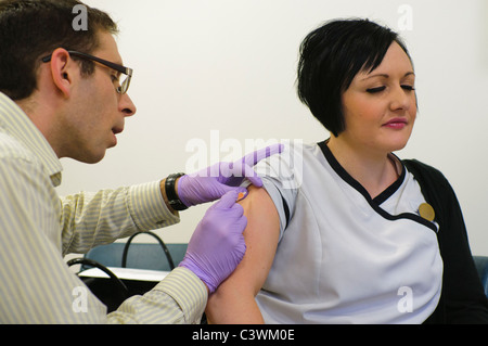 Medico somministra pandemrix vaccino per H1N1 virus influenzale (influenza suina) per un paziente di sesso femminile Foto Stock