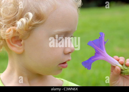 Eco Friendly blondie girl staring al fiore violaceo Foto Stock