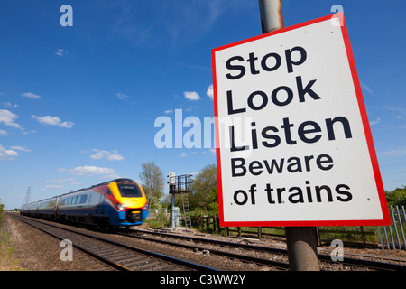 Smettere di guardare ascoltare attenti di treni firmare da un treno in movimento passando un incrocio ferroviario cartello segnaletico Inghilterra GB UK Europa Foto Stock