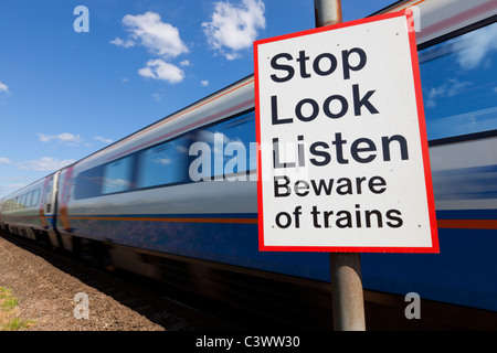 Smettere di guardare ascoltare attenti di treni firmare da un treno in movimento passando un incrocio ferroviario cartello segnaletico Inghilterra GB UK Europa Foto Stock