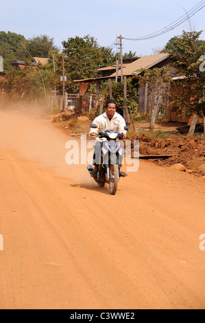 Moto accelerando lungo la strada polverosa in Bou Sraa village, zone di Mondulkiri Provincia, in Cambogia. Foto Stock