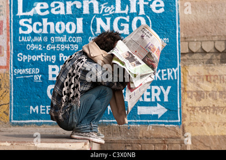 Un uomo che legge il giornale in Varanasi Foto Stock