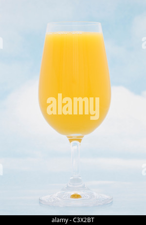 A glass of fresh orange juice against blue sky background Foto Stock