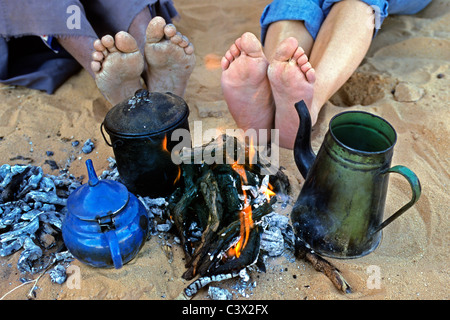 Algeria, Djanet, il Deserto del Sahara, piedi di uomo delle tribù Tuareg e turisti. Teiere. Campfire. Foto Stock