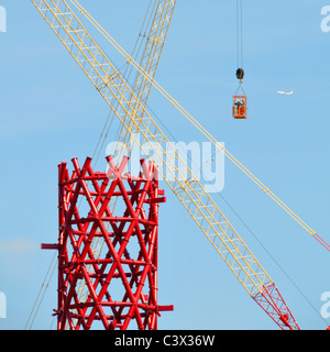 Gru edili incrociata rosso centrale in acciaio strutturale core ArcelorMittal Orbit torre due lavoratori metà aria nella gabbia di accesso Olimpiadi di Londra 2012 REGNO UNITO Foto Stock