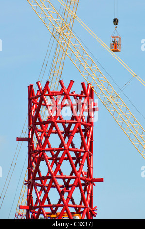 Gru edili incrociata rosso centrale in acciaio strutturale core ArcelorMittal Orbit torre due lavoratori metà aria nella gabbia di accesso Olimpiadi di Londra 2012 REGNO UNITO Foto Stock