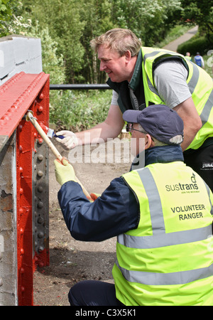 Sustrans volontario rangers lavori di verniciatura di un ponte sulla costa a costa c2c pista ciclabile a Stanley, NE L'Inghilterra, Regno Unito Foto Stock