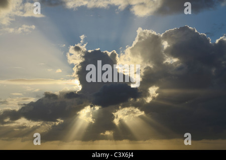 Raggi solari che esplodono attraverso la nuvola al tramonto. Foto Stock