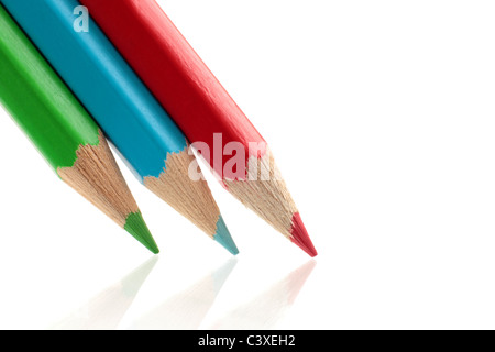 Tre colorate, sharp matite, verde, blu e rosso set contro uno sfondo bianco, con una leggera riflessione. Foto Stock