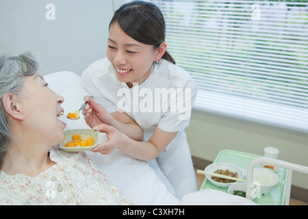 L'infermiera aiutando senior donna mangiare cibo, nella prefettura di Kanagawa, Honshu, Giappone Foto Stock