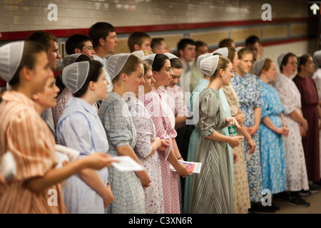 Chiesa mennonita membri cantare inni e passare fuori brochure come loro proselitismo nella metropolitana di New York Foto Stock