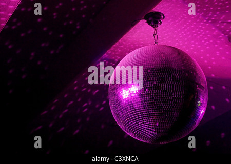 Palla da discoteca in movimento che riflette luce rosa nel night club con spazio di copia Foto Stock