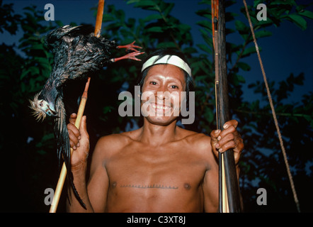 Tribesman Matses con un anatra (piping guan) da Amazon ucciso con il suo arco e frecce. Matses indiani. Amazon, Perù. Foto Stock