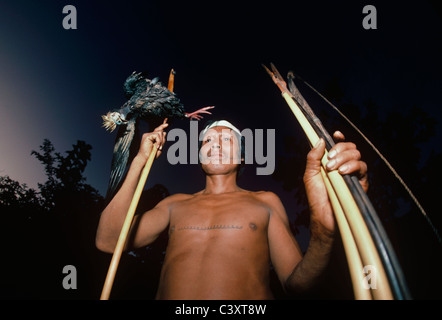 Tribesman Matses con un anatra (piping guan) da Amazon ucciso con il suo arco e frecce. Matses indiani. Amazon, Perù. Foto Stock