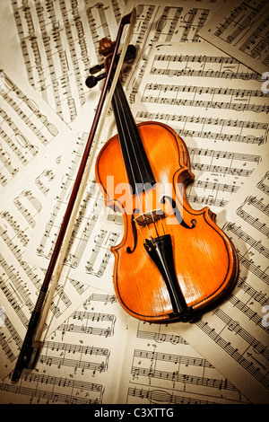 Il legno vecchio violino giacente su note musicali closeup Foto Stock