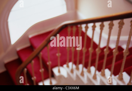 Vista impressioniste di girare in elegante moquette rossa scalone ornato di Bannister e ricurva semi-finestra circolare Foto Stock