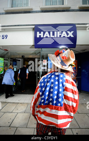 Un vestito in maniera colorata passer da al di fuori di una filiale della Halifax Bank a Cheltenham Regno Unito Foto Stock