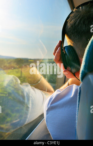 Giovane uomo l'ascolto di musica con cuffie su un viaggio in treno Foto Stock