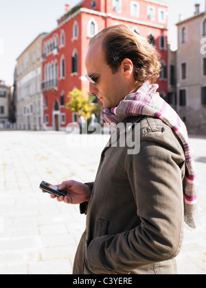 Uomo che guarda il suo telefono in strada Foto Stock