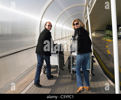 Coppia con i bagagli su un carrello Foto Stock