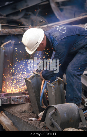 Lavoratore con torcia a gas per il taglio di metallo di scarto. Foto Stock