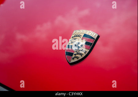 Porsche insegne sul cofano / cofano del motore di un classico guards red 911 con la vernice che riflette il cielo Foto Stock