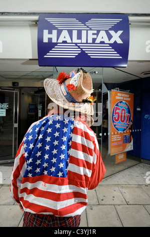 Un vestito in maniera colorata passer da al di fuori di una filiale della Halifax Bank a Cheltenham Regno Unito Foto Stock