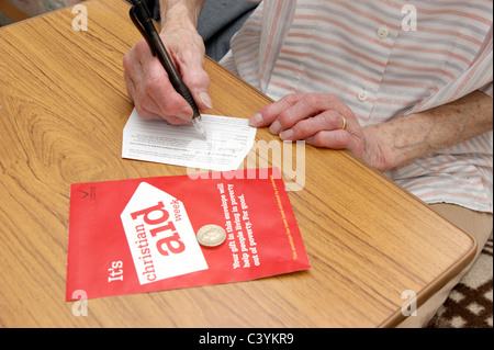 La donna la donazione di Christian Aid settimana & utilizzando il dono aiuto facility per la carità per recuperare imposte indietro Foto Stock